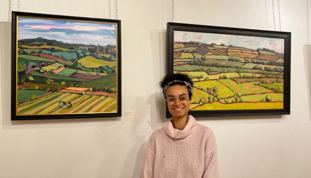 Belinda Millar standing next to two of her paintings displayed in the foyer