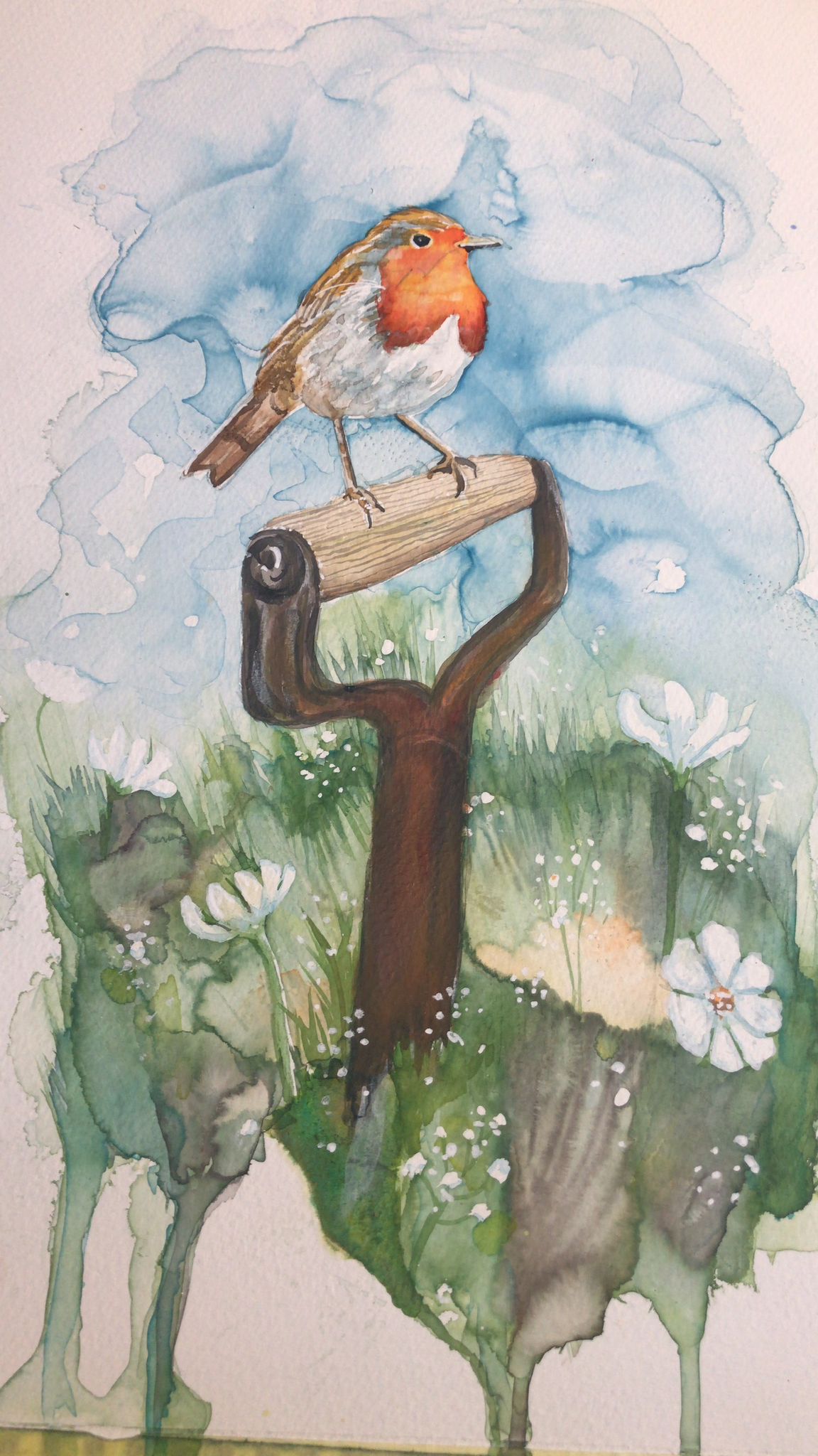 Watercolour painting of a robin perching on a wooden post handle surounded by long grass with white flowers and a blue sky above
